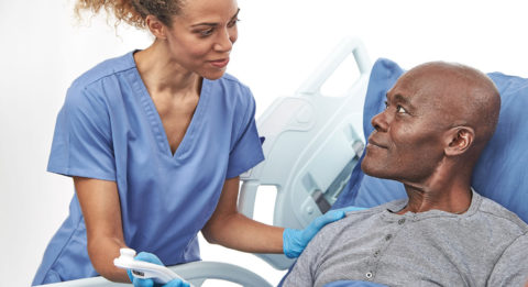dark skin toned female nurse showing dark skinned toned male patient the Provizio SEM scanner